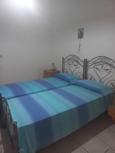 ein blaues Bett mit einer schwarzen und blauen Decke in der Unterkunft Casa Marchello in Castrignano del Capo