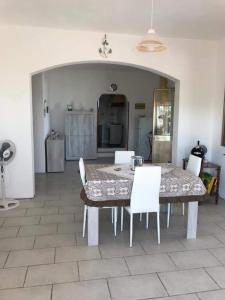 ein Esszimmer mit einem Tisch und weißen Stühlen in der Unterkunft Casa Marchello in Castrignano del Capo