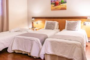 Habitación de hotel con 2 camas con sábanas blancas en Dexter Hotel - Volta Redonda, en Volta Redonda