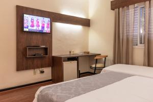 a hotel room with two beds and a tv at Dexter Hotel - Volta Redonda in Volta Redonda