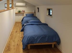 2 Betten mit blauen Bettdecken in einem Zimmer in der Unterkunft ワンちゃんと泊まれるコテージ　西野納屋 in Kujukuri