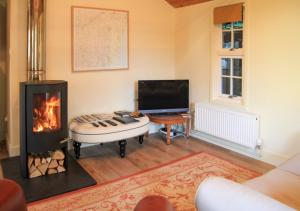 een woonkamer met een open haard en een televisie bij Garden Lodge in Worlingworth