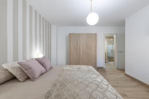 um quarto branco com uma cama e um corredor em Neptuno Deluxe em Granada