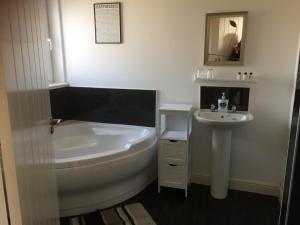 un bagno bianco con vasca e lavandino di Dha Urlar a Bowmore