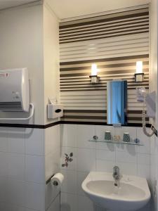 ein weißes Badezimmer mit einem Waschbecken und einem Spiegel in der Unterkunft Hotel Val De Loire in Tours