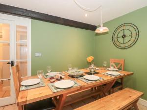 a dining room with a wooden table and a clock on the wall at The Grain Store in Weymouth