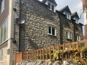 a stone house with a wooden fence in front of it at The Grain Store in Weymouth