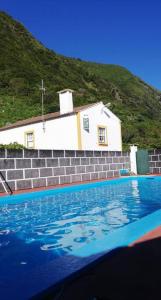 uma pequena capela branca com uma casa atrás de uma piscina em Quinta do Girassol - AL 