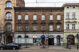 un gran edificio de ladrillo con un coche aparcado delante de él en Apartament Vinci, en Cracovia
