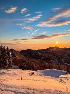 una puesta de sol en la cima de una montaña cubierta de nieve en Resort Monte Poieto, en Aviatico