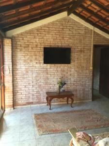 a television on a brick wall with a table at Elviajero in Campinas