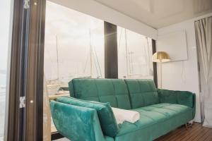 a green couch in a living room with a window at Floating Experience - Casa flutuante a 25 min do Porto in Póvoa de Varzim