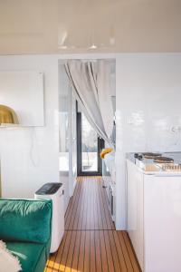a kitchen with white cabinets and a green couch at Floating Experience - Casa flutuante a 25 min do Porto in Póvoa de Varzim