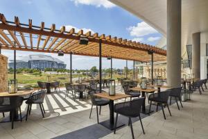 ein Restaurant mit Tischen und Stühlen auf einer Terrasse in der Unterkunft Live! by Loews - Arlington, TX in Arlington