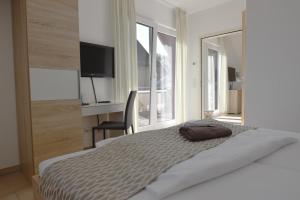 a bedroom with a bed and a desk with a television at PASTORI - Das historische Lichtspielgasthaus in Weilmünster +11 photos