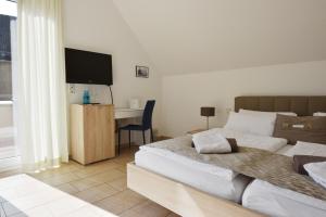 a bedroom with two beds and a desk with a television at PASTORI - Das historische Lichtspielgasthaus in Weilmünster
