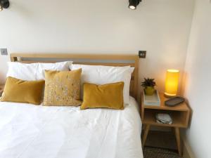 een bed met gele kussens en een lamp op een tafel bij The Cowshed in Merrymeet