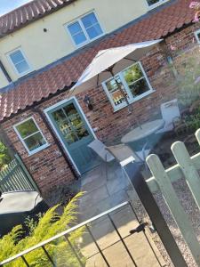 a house with an umbrella and a table and chairs at Two Bedroomed House near Newark & Grantham 