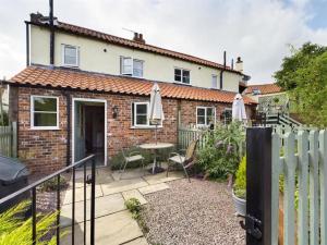 Cette maison en briques dispose d'une terrasse avec une table et des chaises. dans l'établissement Two Bedroomed House near Newark & Grantham, 