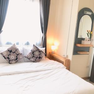 1 dormitorio con cama blanca con almohadas y espejo en Teenan Hostel, en Nan