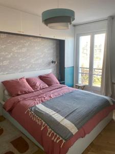 a bedroom with a bed with pink pillows and a window at T3 moderne & proche stade de France, Adidas Arena in Saint-Denis