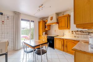 - une cuisine avec des placards en bois, une table et des chaises dans l'établissement Chez Laurent, à Épagny