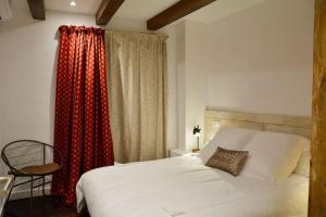 ein Schlafzimmer mit einem weißen Bett und einem Stuhl in der Unterkunft Can Senio 2 in Tossa de Mar
