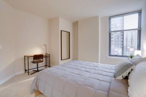 a white bedroom with a large bed and a desk at Amazing 2 BR Apartment Located at Pentagon City in Arlington