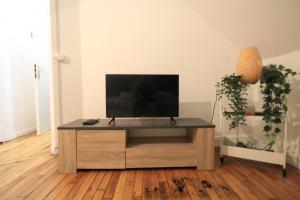 a living room with a tv on a wooden entertainment center at 10mn RER B Aéroport CDG - Paris Gare du Nord, T11 Express, Le Bourget, Tout équipé, Netflix Gratuit, 3 personnes, 4ème étage, escaliers, Parc des Expositions, Parking rue Gratuit après 19h in Drancy