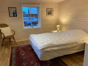 um quarto com uma cama, uma cadeira e uma janela em ELGGÅRDEN em Torup