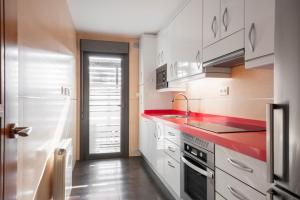 una cocina con armarios blancos y encimeras rojas en EnjoyGranada EMIR 4C + Parking, en Granada