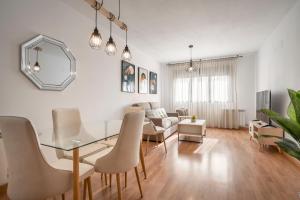 uma sala de estar com uma mesa de vidro e cadeiras em EnjoyGranada EMIR 4C + Parking em Granada
