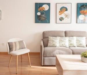 uma sala de estar com um sofá e uma cadeira em EnjoyGranada EMIR 4C + Parking em Granada