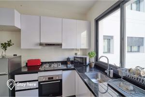 a kitchen with white cabinets and a sink and a window at Stayhere Rabat - Hay Riad - Sophisticated Residence in Rabat