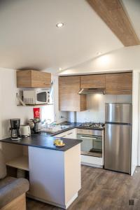 a kitchen with stainless steel appliances and wooden cabinets at amorosa mobil home in Canet-en-Roussillon