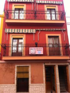un edificio rosso con balcone e insegna sopra di Hostal Senero a Mérida