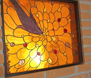 a stained glass window of a flower with a butterfly at Shuttered Dreams Murano Venice in Murano