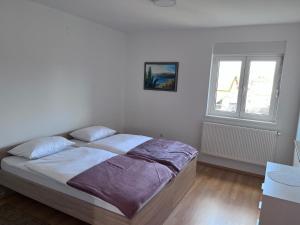 uma cama num quarto branco com uma janela em Apartman Magnolia em Petrovina Turopoljska