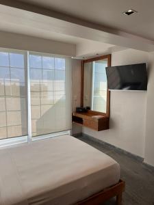 een slaapkamer met een bed en een flatscreen-tv bij Hotel Plaza Kokai Cancún in Cancun