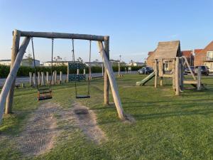 a playground with a swing set in the grass at Newt's Place in Filey
