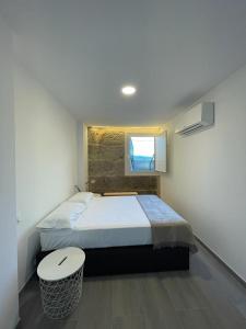 a bedroom with a bed with a stool and a window at Cepas Da Cuenga in Ribadavia