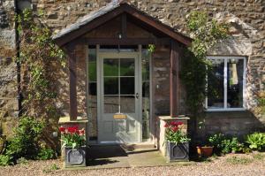 an entrance to a stone cottage with red flowers at Rose Cottage in Tunstall