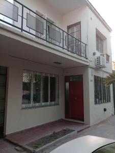 Casa blanca con puerta roja y balcón en Pasteur B&B en Godoy Cruz