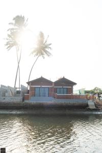 a house on the water with two palm trees at Reunion Ocean Tides in Udupi