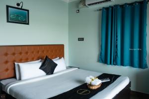 a hotel room with a bed with blue curtains at Reunion Ocean Tides in Udupi
