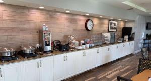 a kitchen with white cabinets and a clock on the wall at SureStay Plus Hotel by Best Western Vero Beach in Vero Beach
