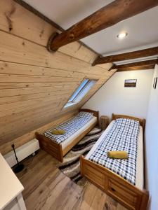 two beds in a room with wooden ceilings at Pokoje gościnne 28 w skosie in Zawadka
