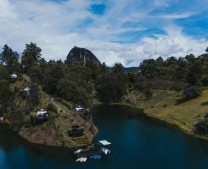 an island in a river with a mountain in the background at Domus Glamping in Guatapé