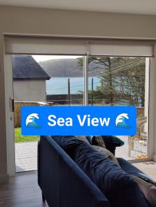 een bank met het logo met uitzicht op zee voor een raam bij Crow's Nest Glandore - 2 - Self Catering in Glandore