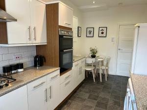 a kitchen with white cabinets and a table with chairs at Light And Spacious Highcross Apartment in Poulton le Fylde